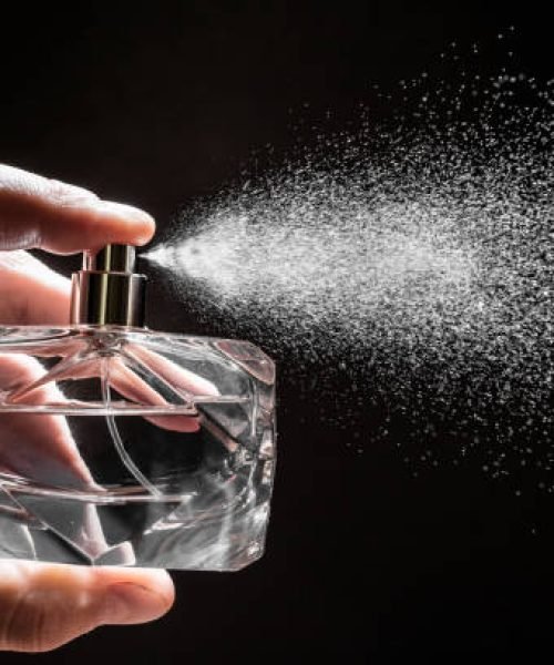 spraying perfume on dark background, closeup  - Image